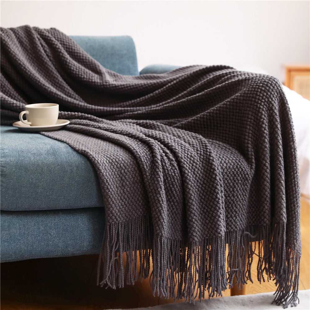 Anas pineapple grid knit throw blanket draped over sofa in Dark Grey with fringe