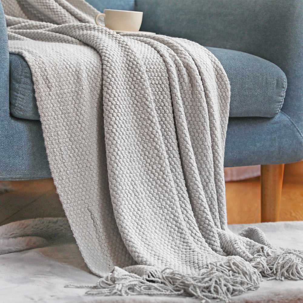 Anas pineapple grid knit throw blanket draped over sofa in Light Grey with fringe