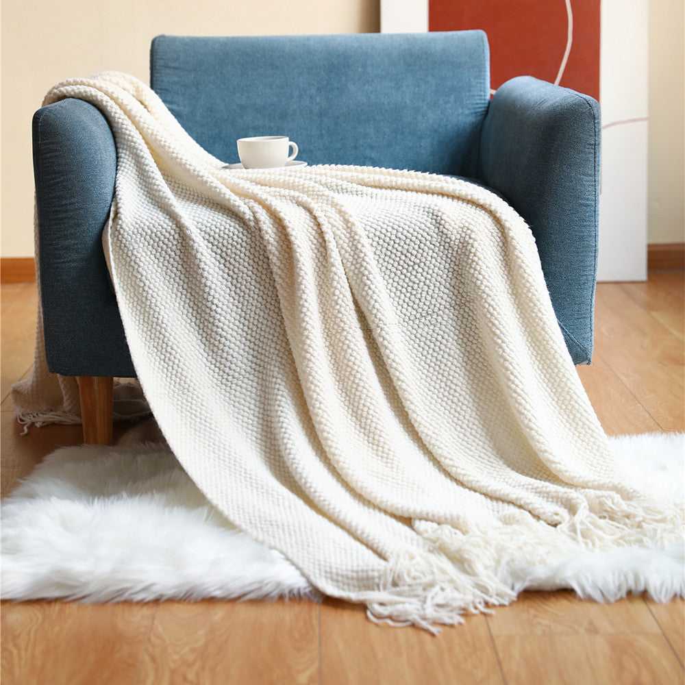 Anas pineapple grid knit throw blanket draped over armchair in White with fringe