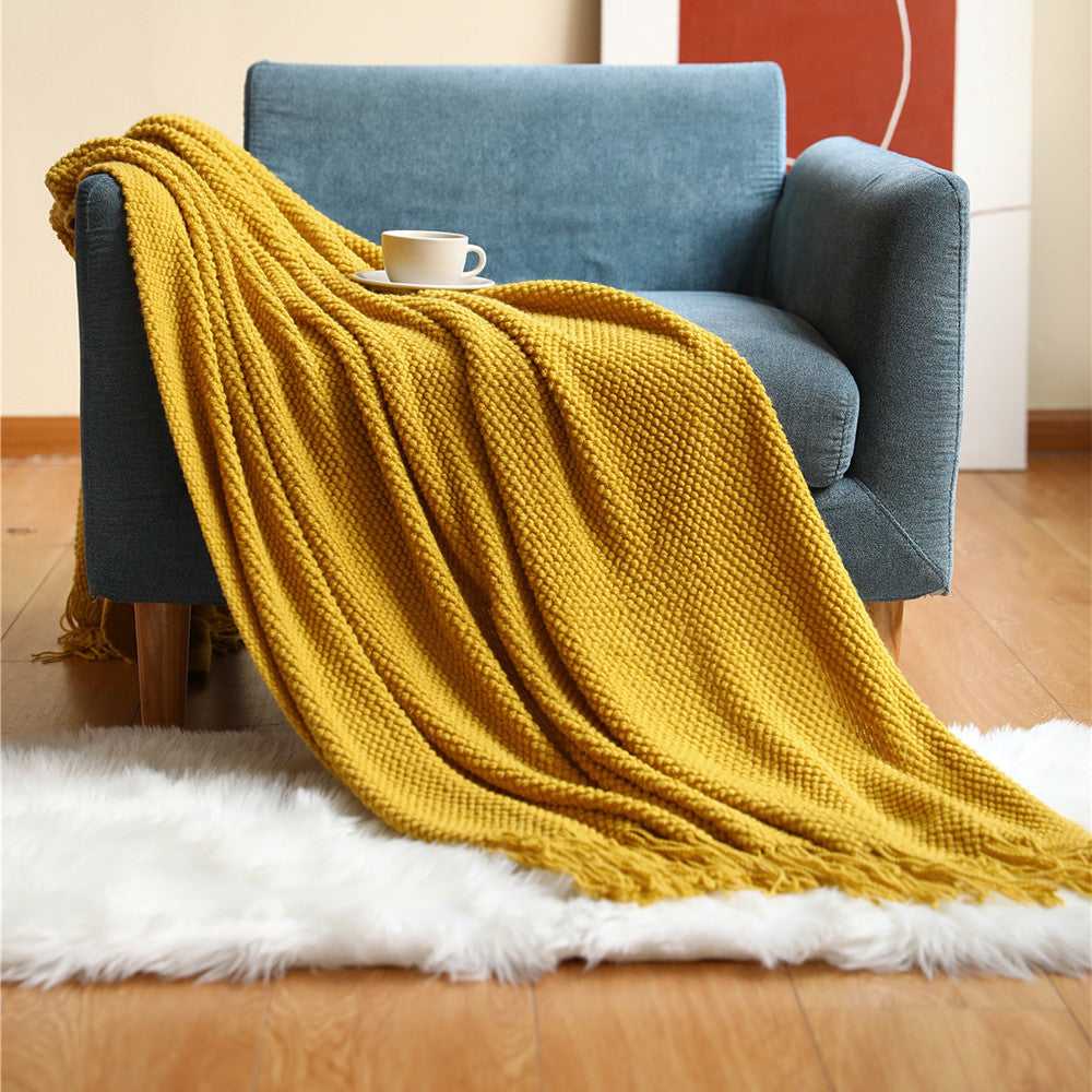 Anas pineapple grid knit throw blanket draped over armchair in Yellow with fringe