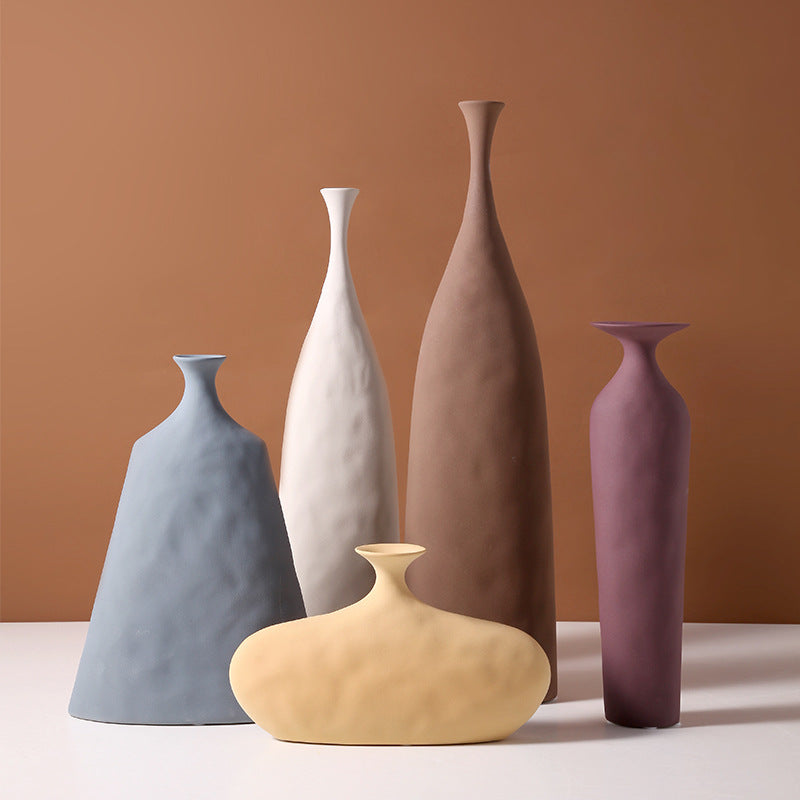 Hecho decorative ceramic vase set in all 5 colors – blue, white, brown, yellow and burgundy – styled against warm terracotta background