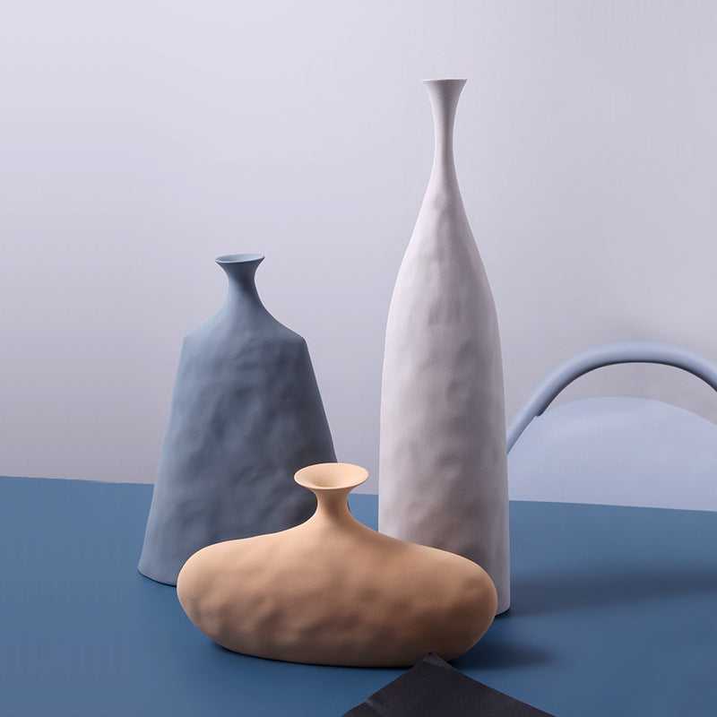 Hecho Nordic ceramic vase collection in blue, white and yellow styled on blue surface – minimalist home decor